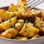 Pinterest graphic of a fork lifting out a bite of air fryer Greek lemon potatoes.