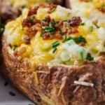 Pinterest graphic of a close view of an air fryer twice baked potato topped with chopped chives and bacon bits.