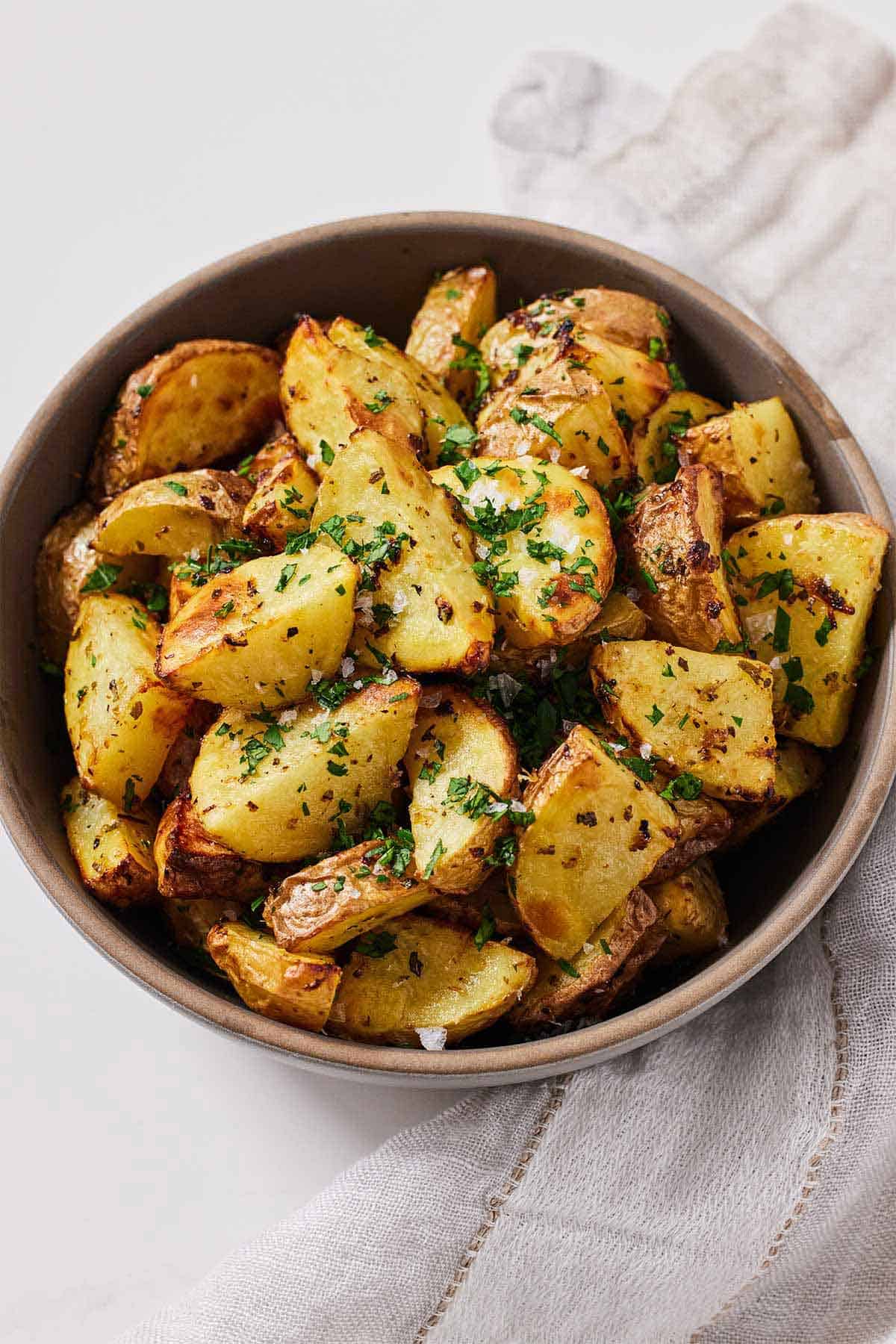 A bowl of air fryer Greek lemon potatoes with chopped parsley on top.
